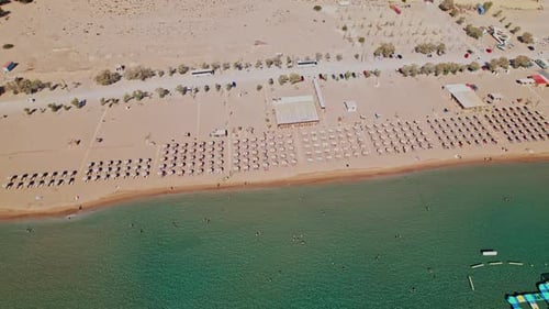 Aerial view of a sunny beach with umbrellas and blue water
