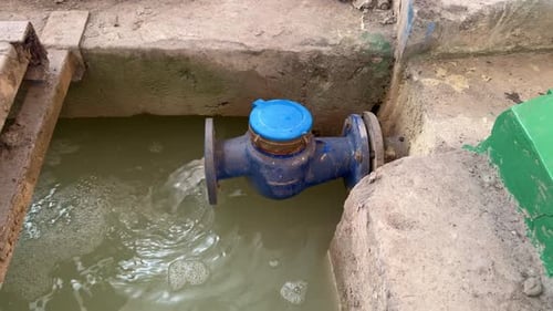 Water Meter in Concrete Enclosure with Flowing Water