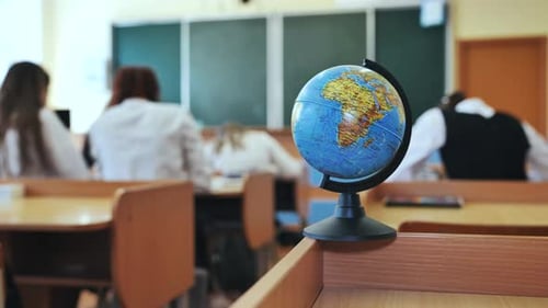 Ein Globus mit Lehrbüchern im Hintergrund einer Unterrichtsstunde in einem Schulklassenzimmer