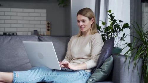 Woman Using Laptop Relaxing on Couch at Home
