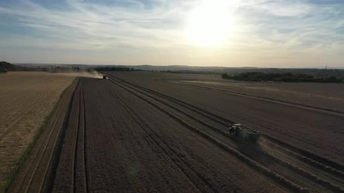 Luftbild von Landmaschinen auf einem landwirtschaftlichen Feld, beim Sammeln von Weizen an einem sonnigen Abend, Drohnenaufnahme