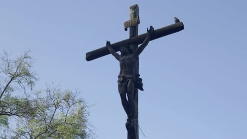 Crucifix Statue of Jesus Christ on a Weathered Wooden Cross Under Clear Skies