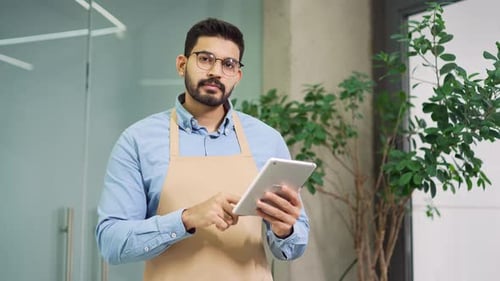 Smiling Man Using Tablet in Workplace Setting