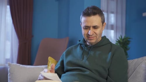 Man Reading a Book on Couch Indoors