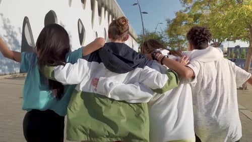 Multiethnic Group of Young Happy Friends Walking Down the Street Holding Each Other Affectionately