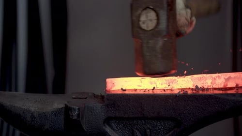 Close Up Blacksmith Hammering Red Hot Steel On An Anvil