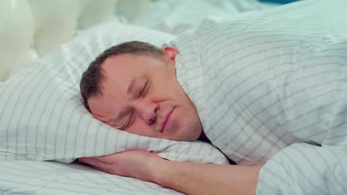 Man Sleeping Peacefully Under Covers in Bed