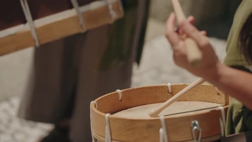 CloseUp of person playing traditional drum with drumstick emphasizing rhythmic performance