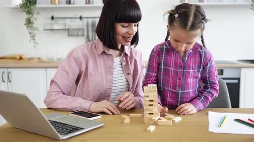 Mutter und Tochter spielen zu Hause zusammen Jenga