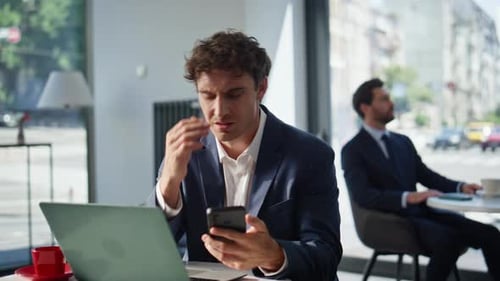 Nervous Manager Looking Cellphone Sitting at Cafe Table with Laptop Closeup
