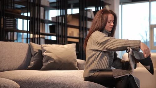 Woman Looking at Samples of Colorful Fabrics Choosing Material for Sofa in Furniture Showroom