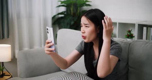 A young woman quarrels with her boyfriend over a video call, looking irritated and upset.