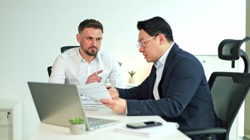 Businessmen Discussing Paperwork in Modern Office Meeting