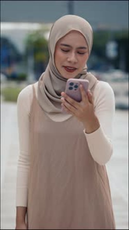 Portrait of Woman Wearing Hijab Smiles As Joins Video Call on Smartphone in City