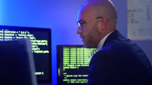 Softwareentwickler codiert in einem Büro auf einem Computer mit mehreren Bildschirmen, auf denen Code angezeigt wird