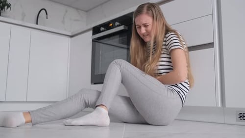 Der monatliche Zyklus einer Frau: Sie sitzt und umarmt ihre Knie, fühlt Verzweiflung und Angst, Einsamkeit