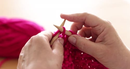 Senior woman knitting with needles indoors, closeup