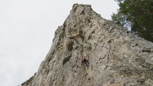 Female Climber Ascending Steep Rocky Cliff