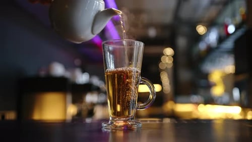 Hot Tea is Poured Into a Glass on the Bar Counter in a Cafe Closeup