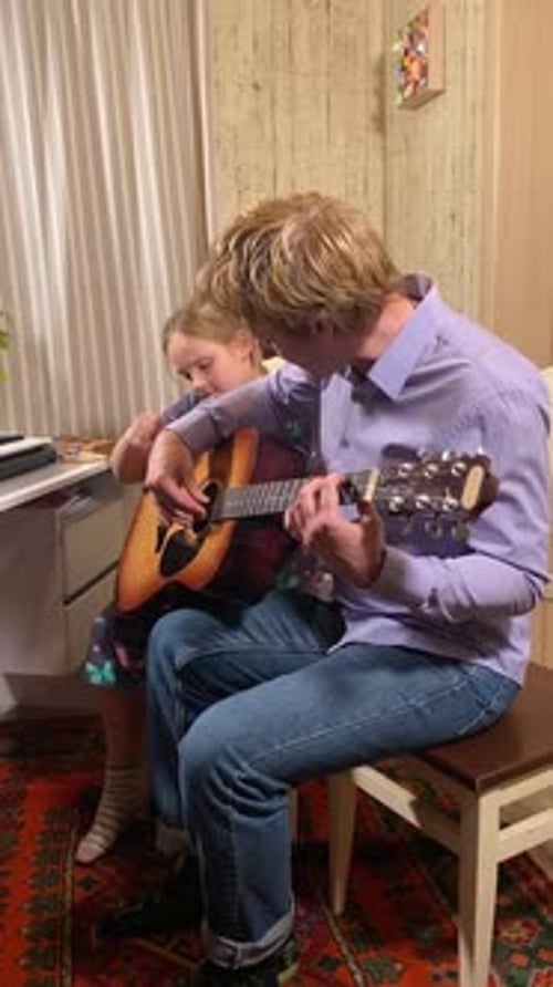Man Teaching Child Guitar in Home Setting
