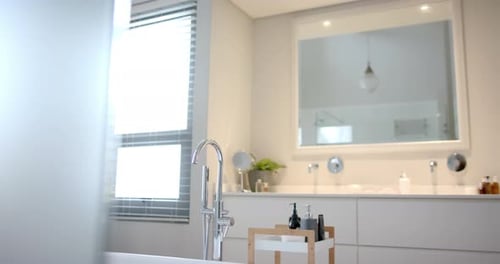 Close up of sunny white bathroom with freestanding bathtub, slow motion
