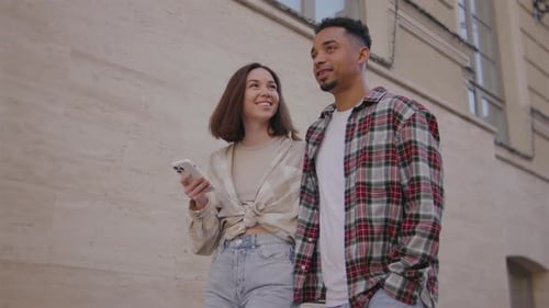 Multiethnic Couple in Love Walks Along the Narrow Streets of a European City The Guy and the Girl