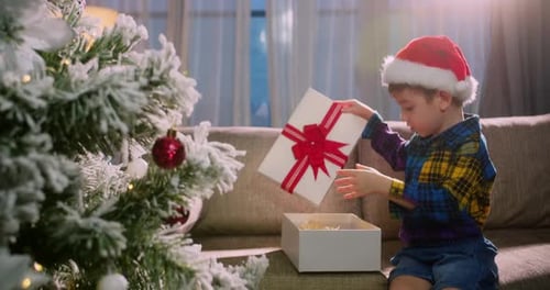 Young Child Opens Christmas Gift on Sofa