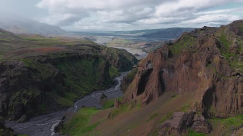 Luftaufnahme des zerklüfteten isländischen Tals mit Fluss und Klippen