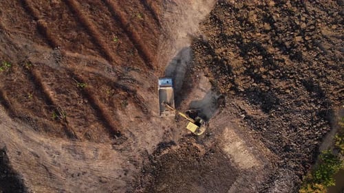 Aerial view of a wheel loader excavator with a backhoe loading sand into a heavy earthmover