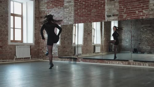 An Attractive Woman in a Sexy Black Outfit Dances in Front of a Mirror in the Studio