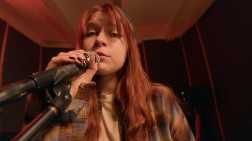 Gen Z Redheaded Girl Singing Into Microphone, Performing in Band in Music Studio