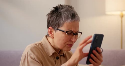 Ältere Frau mit schlechtem Sehvermögen hält Smartphone nah ans Gesicht