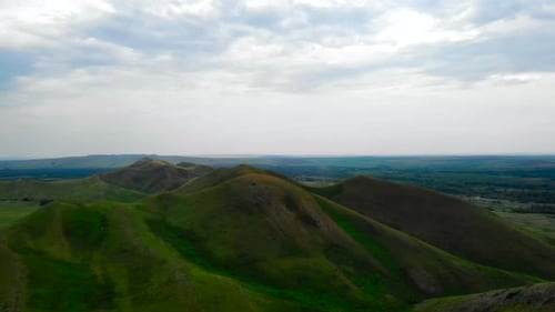 Scenic Green Rolling Hills Under Cloudy Sky Media