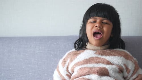 Child Screaming and Crying Sitting on a Sofa at Home