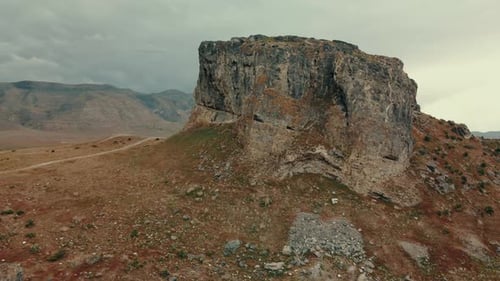 Ascending aerial view behind rock formation to reveal mountain range