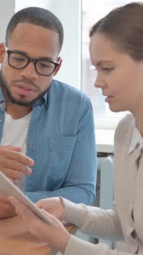 Colleagues Collaborate Looking at Tablet in Workplace