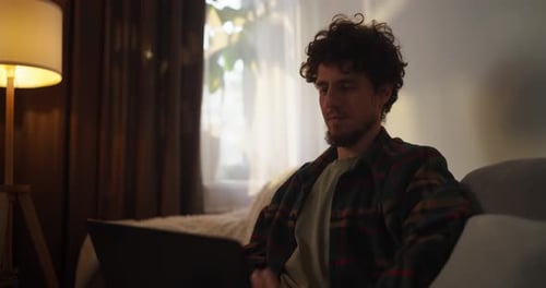 Adult Using Laptop While Sitting on Couch Indoors