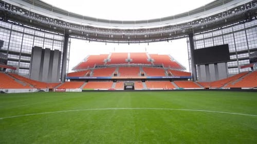 Empty Orange and White Stadium with Green Grass Field