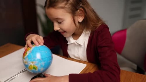 Girl Studying Globe at Desk