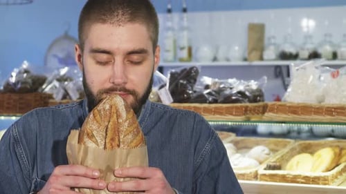 Man Smelling Fresh Bread in Bakery Smiling