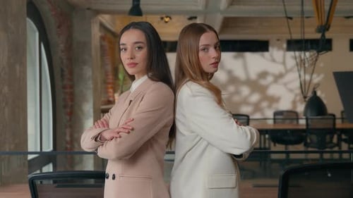 Two Professional Women Standing Back to Back in Office