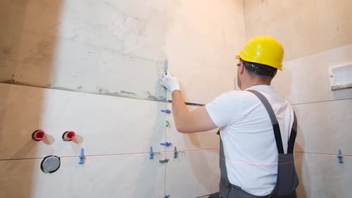 Man Tiling Bathroom Wall with Precision and Care