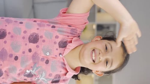 Vertical video of Happy girl child waving at camera.