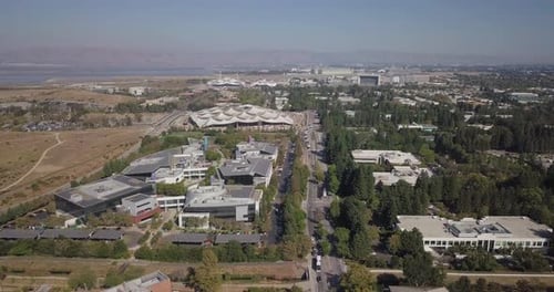 Антенна новой штаб-квартиры Google Plex с солнечными батареями и натяжной конструкцией на крыше в Калифорнии с видом на горы