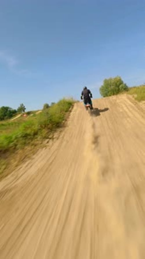 Dirt Bike Jumps Over Hill in Rural Area
