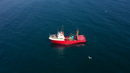 Aerial view to a red fishing vessel in sea