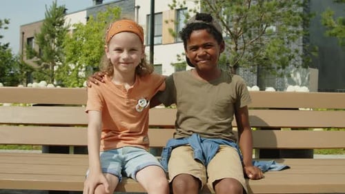 Two Young Friends Sitting Together on Park Bench