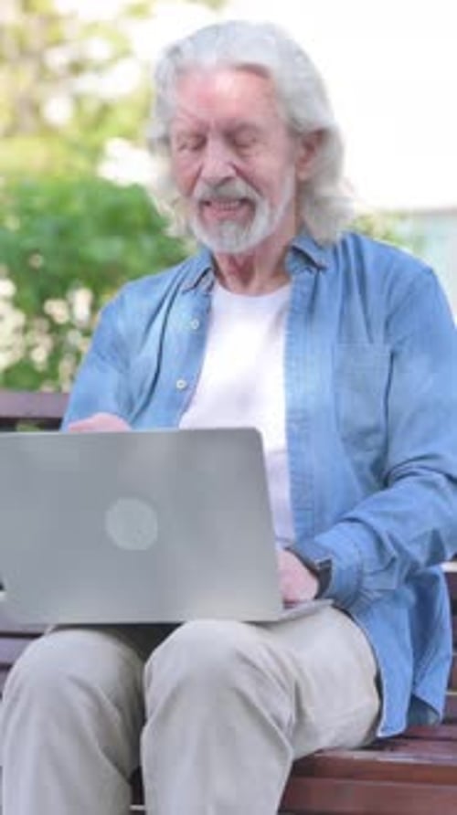 Senior Man Video Chatting on Laptop Outdoors