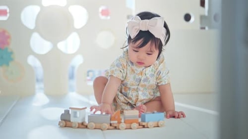 Infant Girl Playing with Wooden Train Toy Indoors