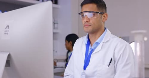 Smiling Man in Lab Coat Using Computer